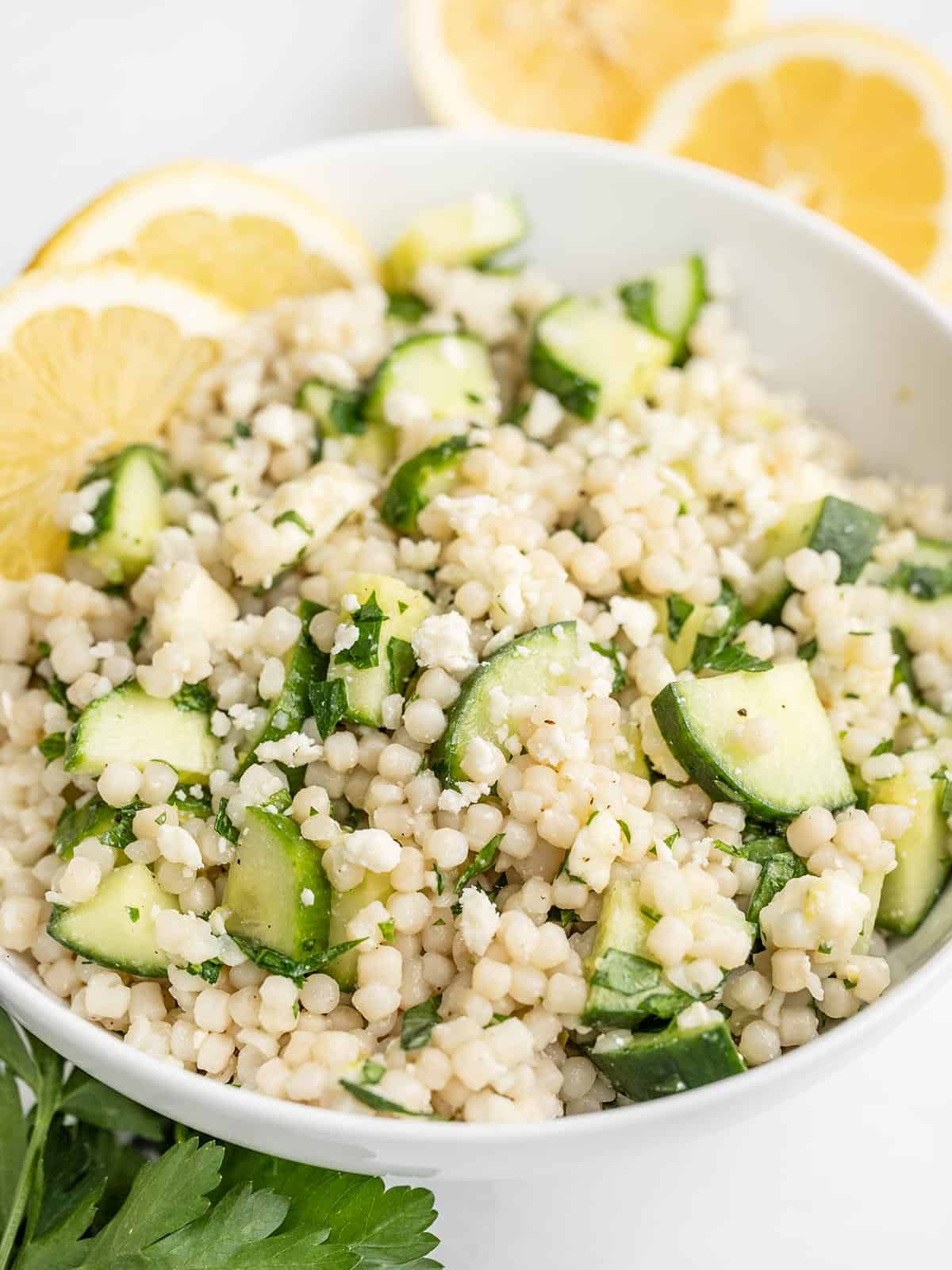 Close up side view of a bowl of lemony cucumber couscous salad.