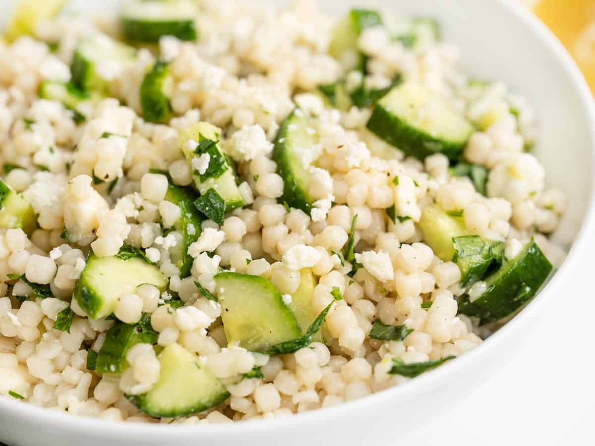 Close up side view of lemony cucumber couscous salad in a bowl. 