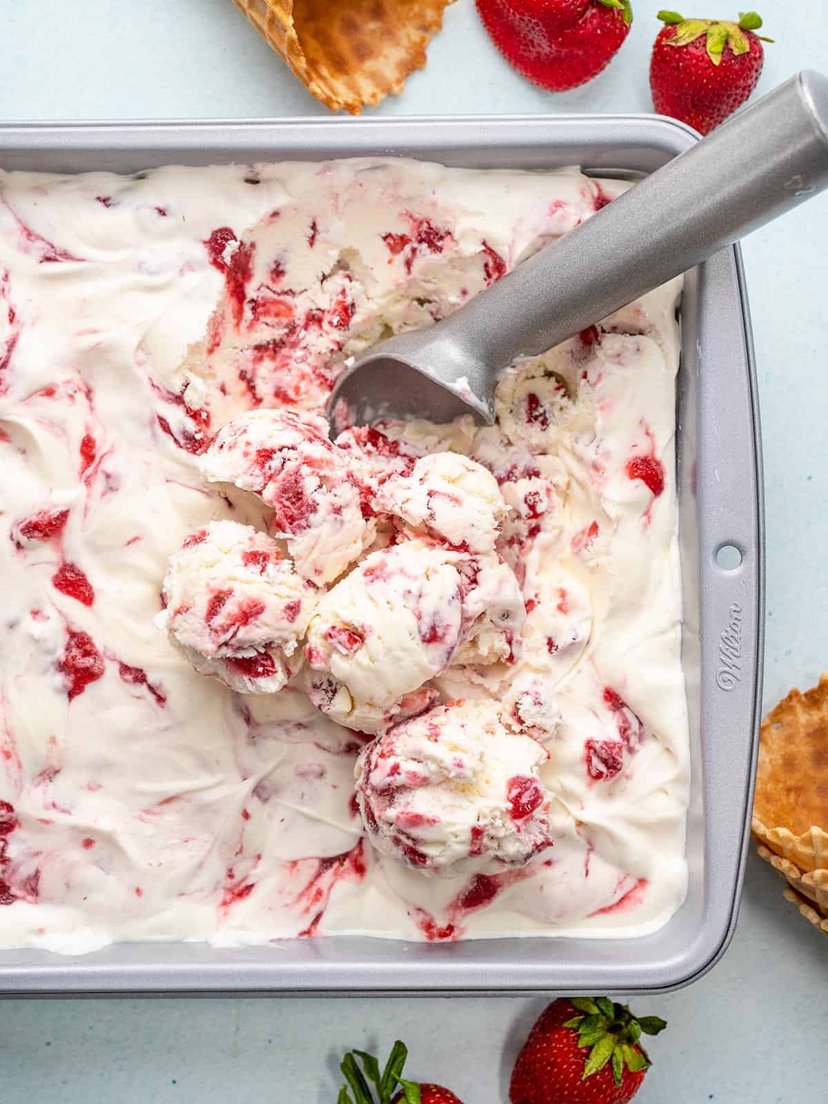 Overhead view of ice cream being scooped out of the dish.