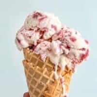 Close up side view of a strawberry ice cream cone.