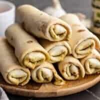 Side view of pesto mozzarella roll ups stacked on a plate.