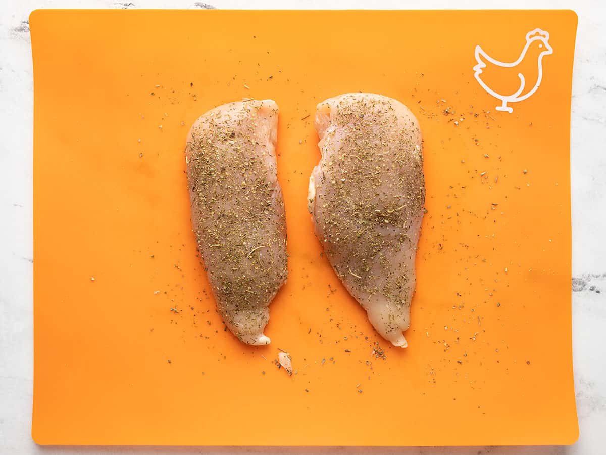 Bir kesme tahtası üzerinde terbiyeli tavuk göğsü.