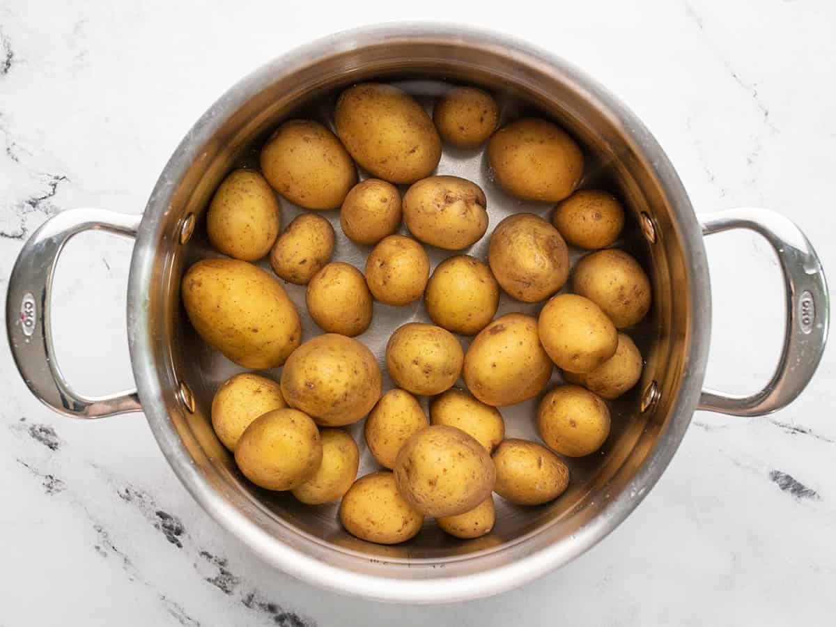 Baby potatoes in a pot with water.