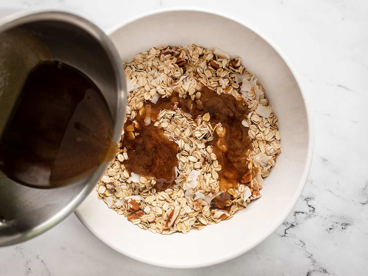 Oil and sugar mixture being poured over the dry granola.