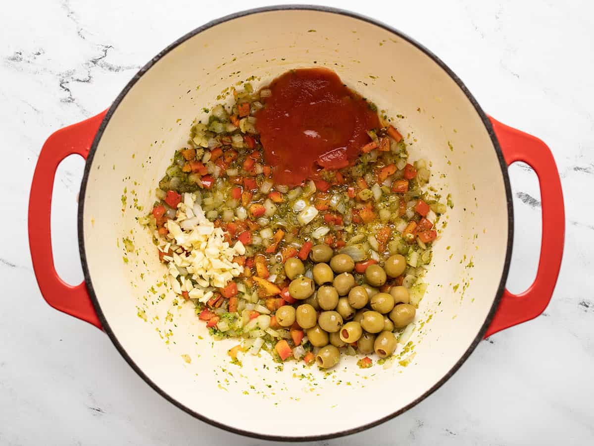 Olives, tomato sauce, and other ingredients browning in a Dutch oven.