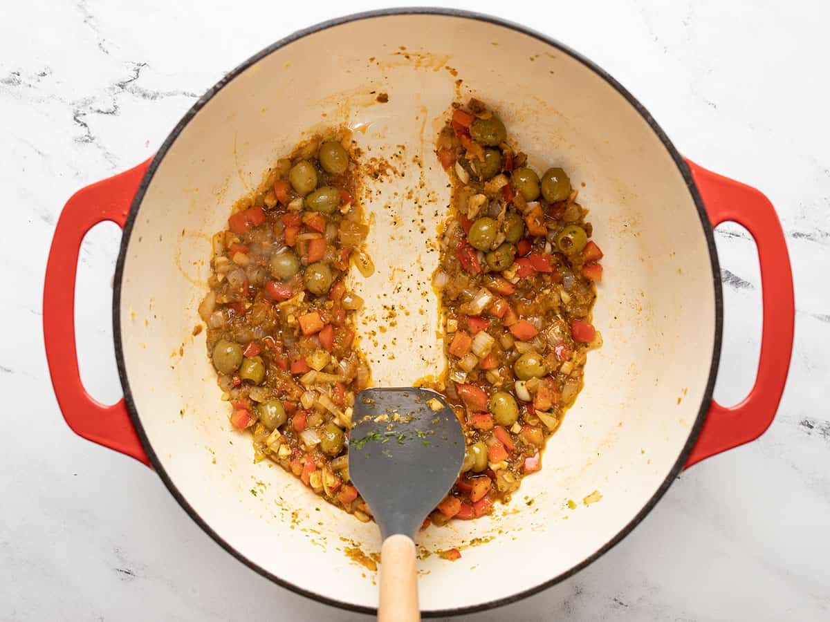 Spatula cutting through ingredients in a red Dutch oven.