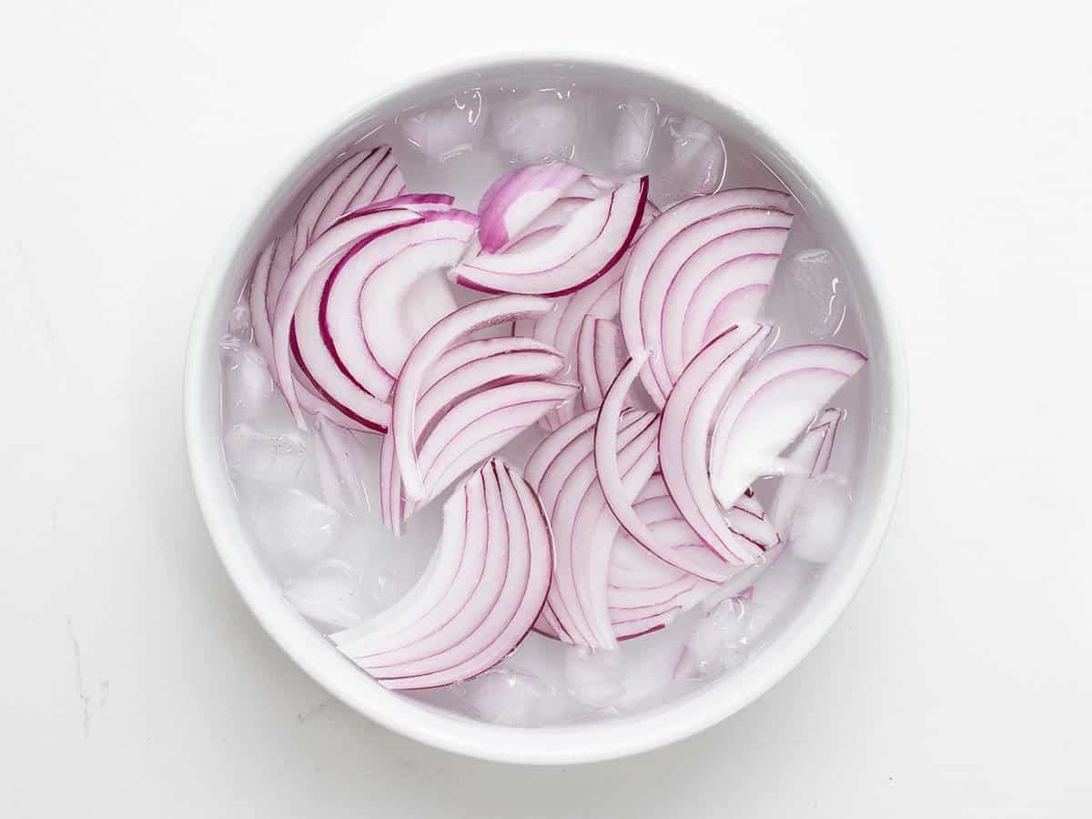 sliced ​​red onion in a bowl of ice water.