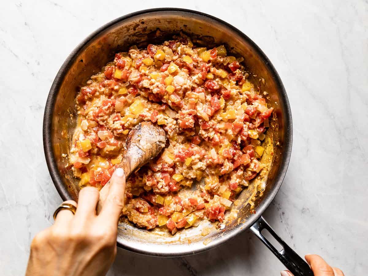 Eggs and vegetables being scrambled in the skillet.