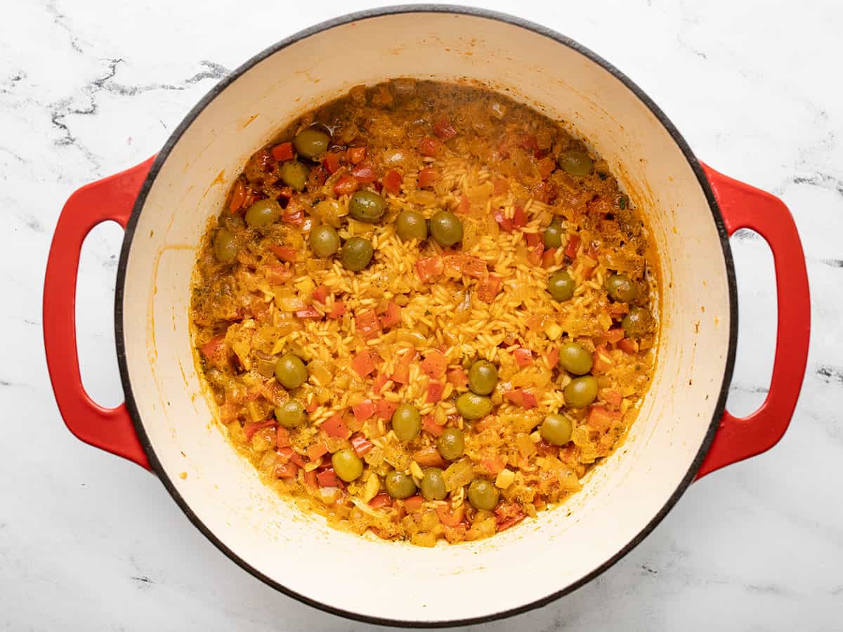 Rice in a red Dutch oven that has had chicken stock cooked out of it.