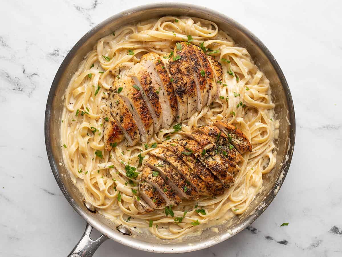Sliced ​​chicken added on top of the pasta alfredo.