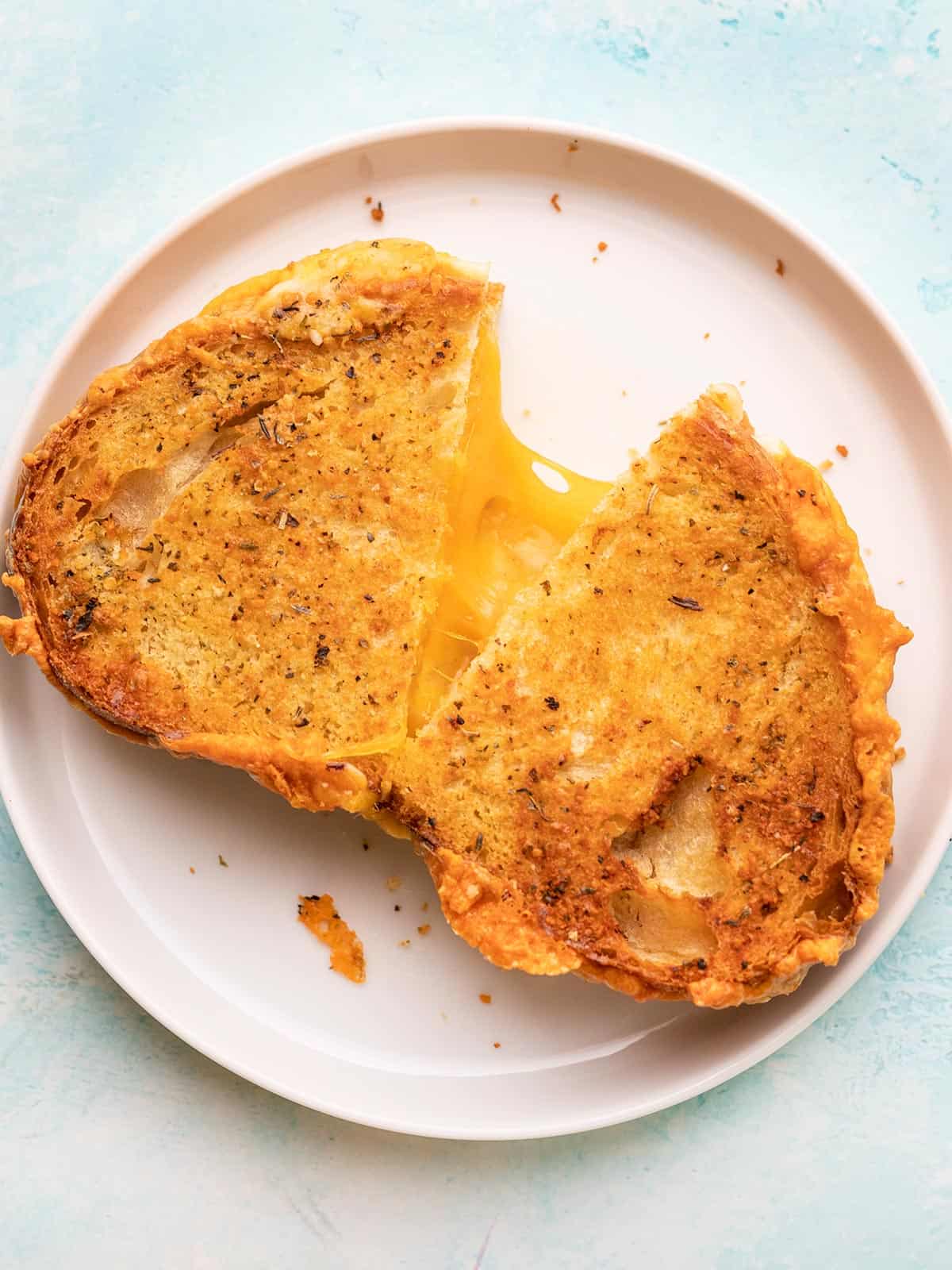Air fryer grilled cheese being pulled apart on a white plate.