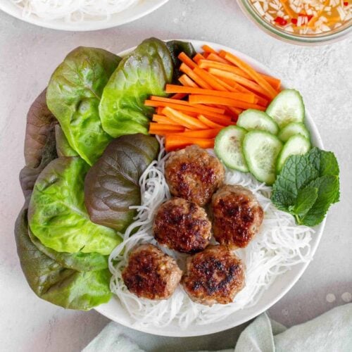 Overhead view of Bún chả in a bowl with noodles and vegetables, dipping sauce on the side.