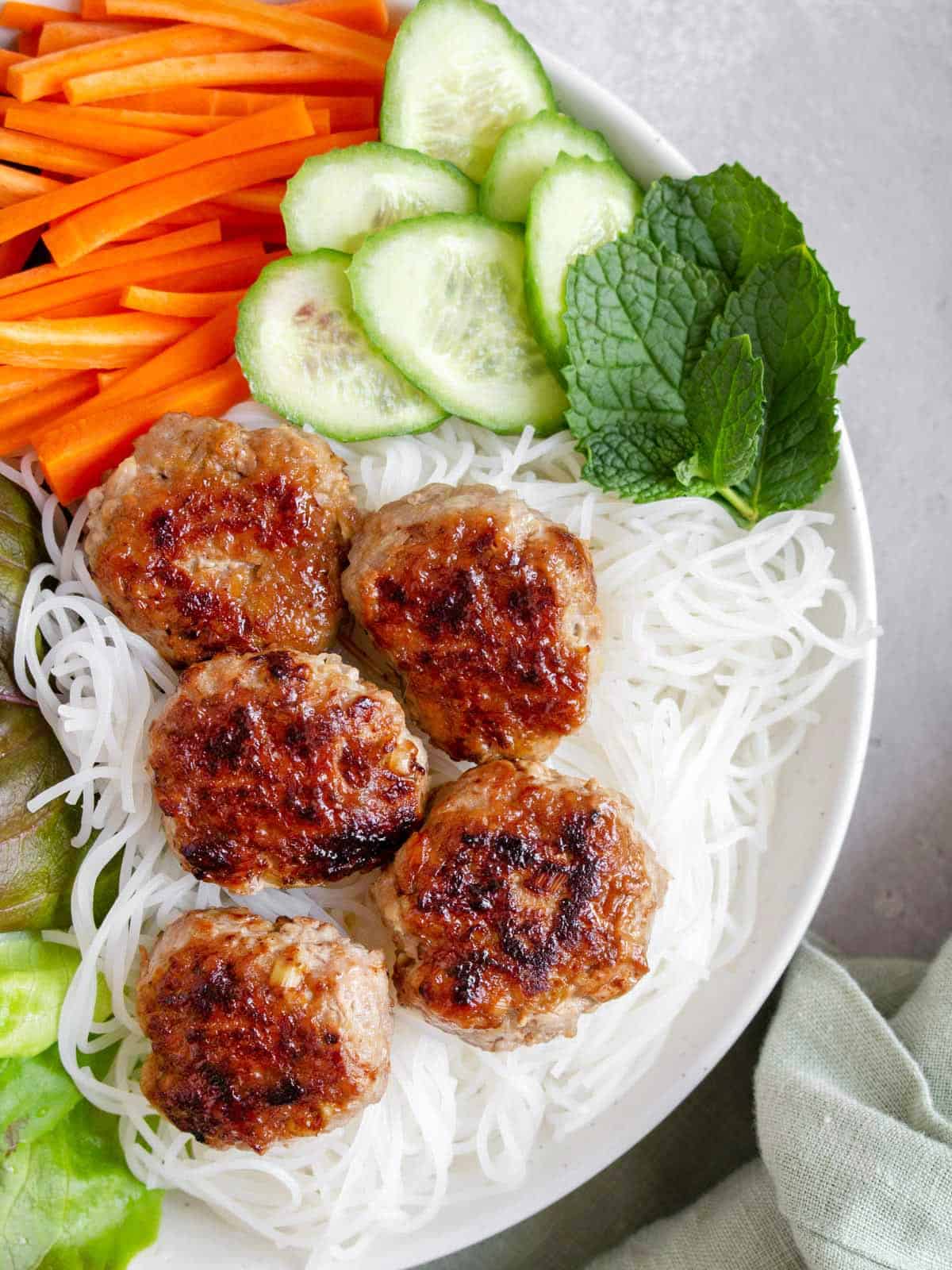 Close up of Bún chả in a bowl with rice noodles and vegetables.