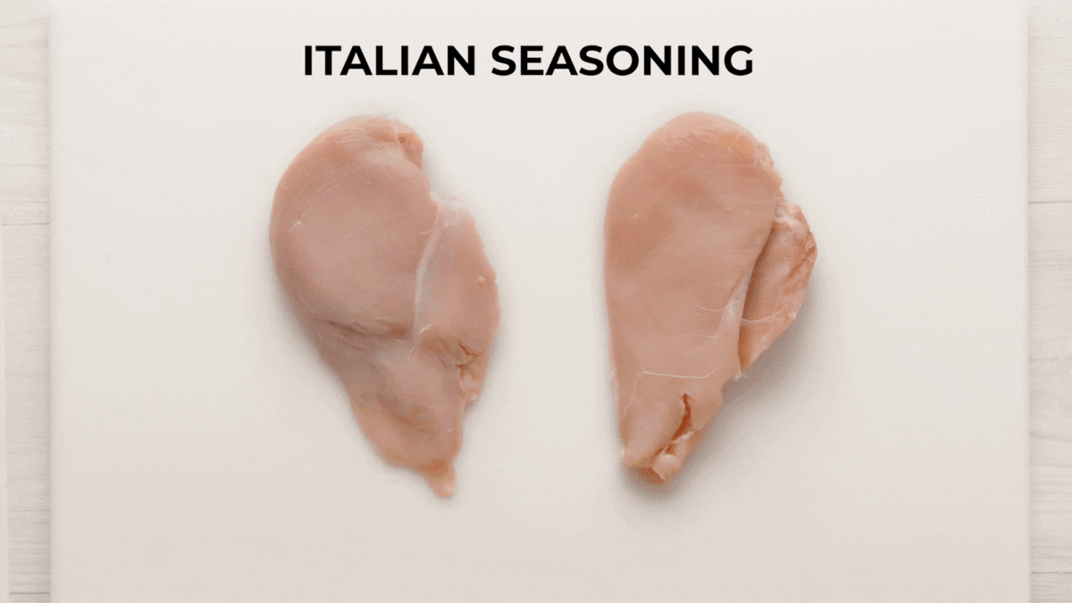 Seasoned chicken breast on a cutting board.