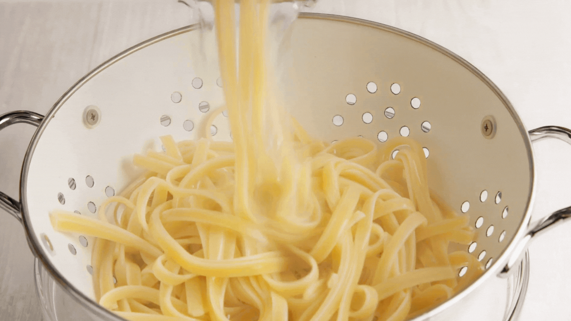 Fettuccine being tossed in the cream sauce.
