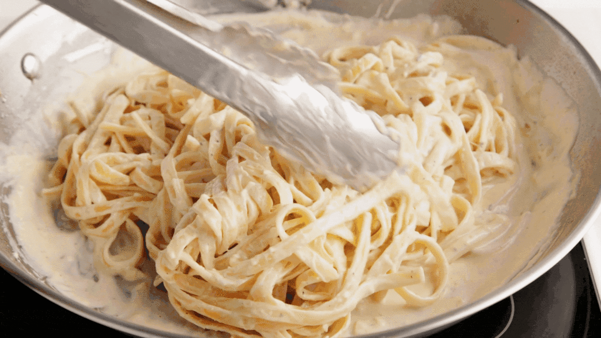 Sliced chicken added on top of the pasta alfredo.