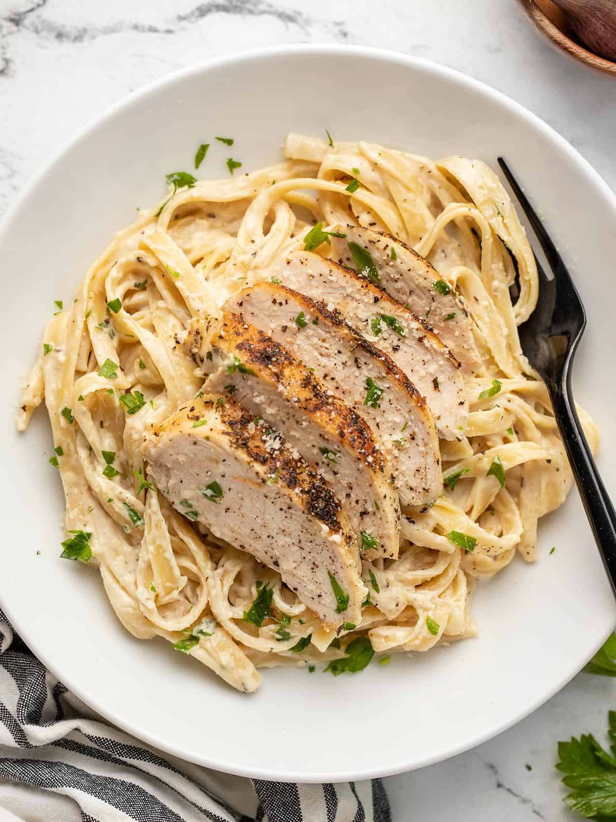 close up overhead view of a bowl full of chicken alfredo pasta.