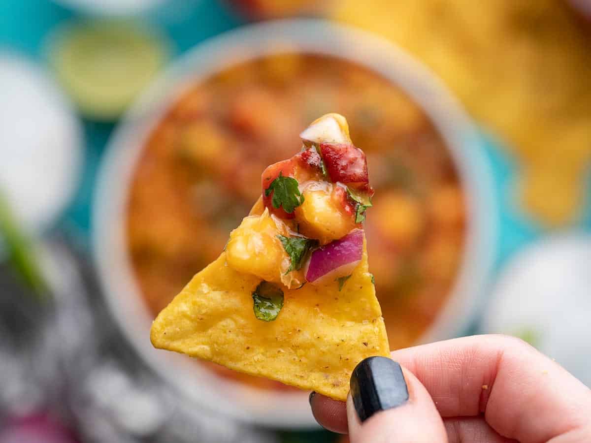 Chipotle Peach Salsa on a chip with the bowl in the background.