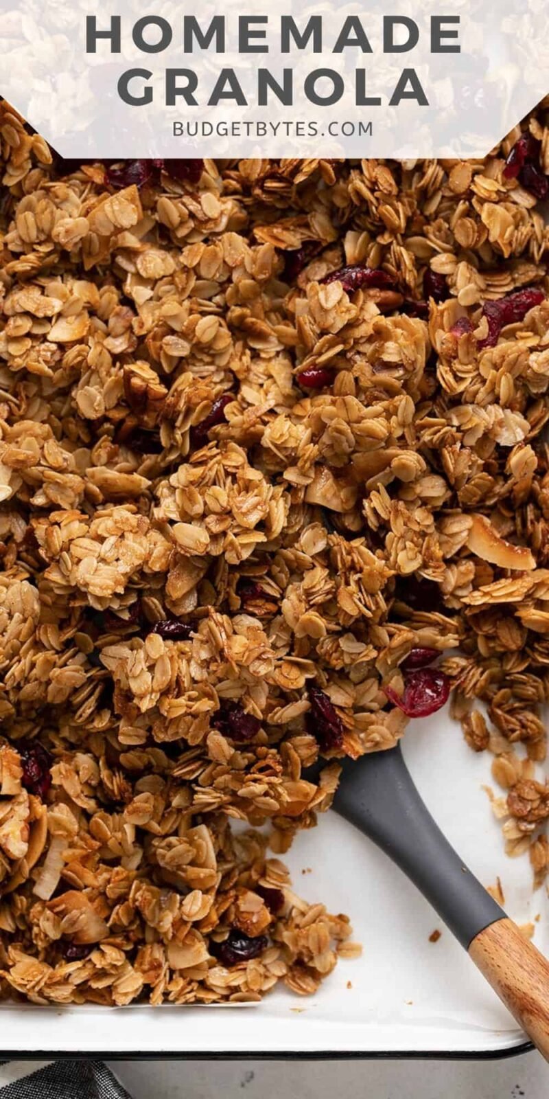 Overhead view of a sheet pan full of granola with a spatula.