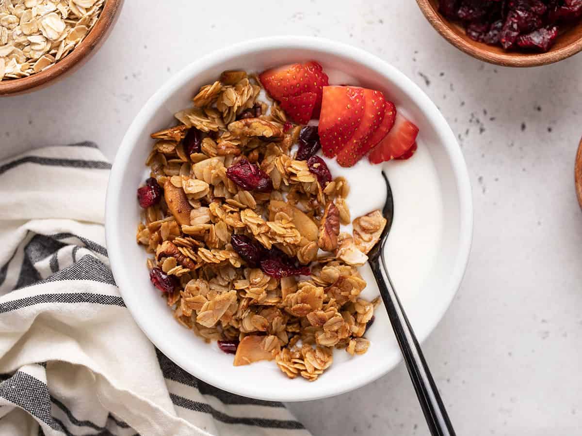 Overhead view of a bowl of yogurt topped with granola and strawberries.