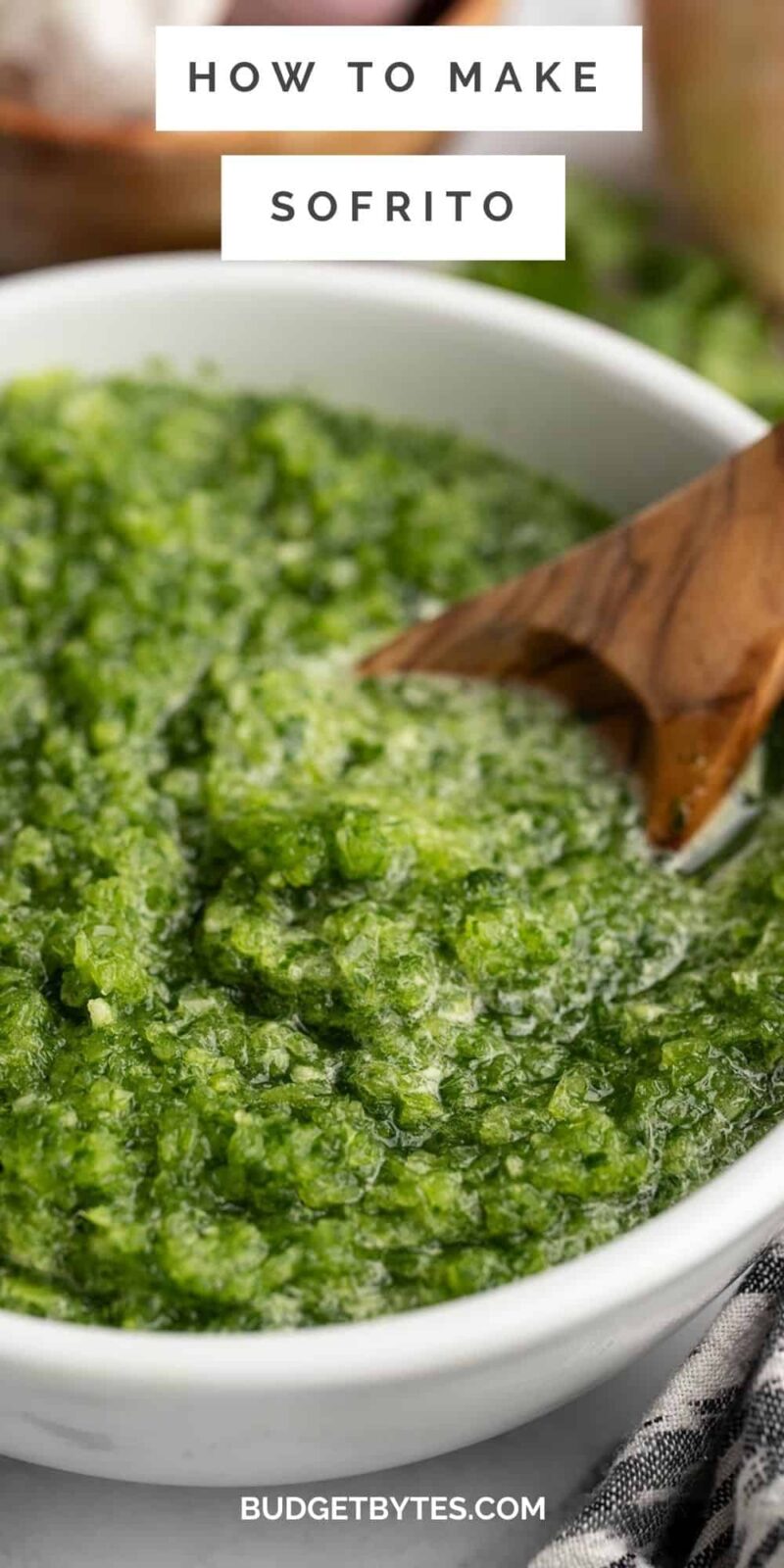 Sofrito in a white bowl with a wood spoon in it.