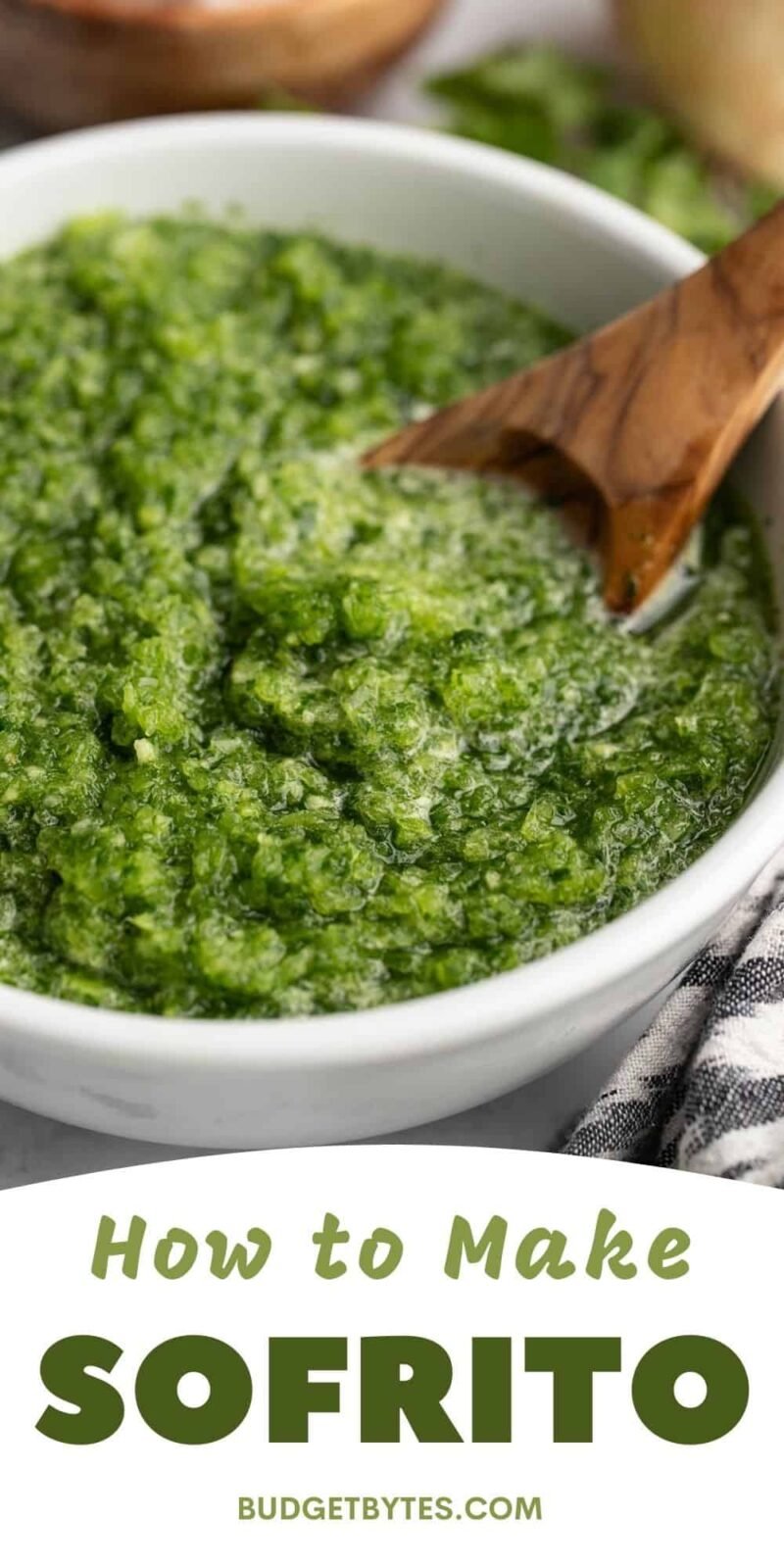 Sofrito in a white bowl with a wooden spoon in it.