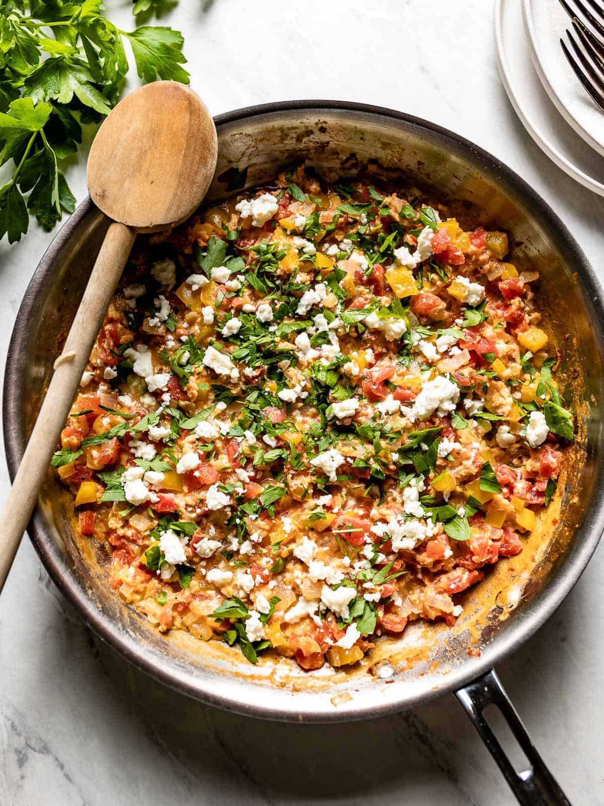 Overhead view of a skillet full of menemen with a wooden spoon.