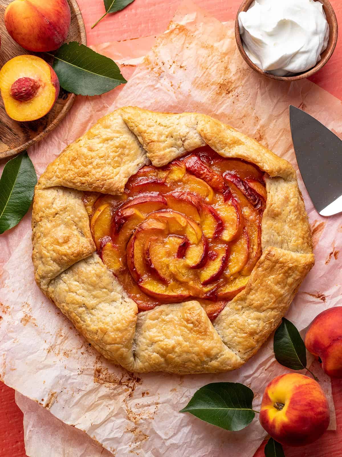 Overhead shot of peach galette surrounded by fresh peaches.