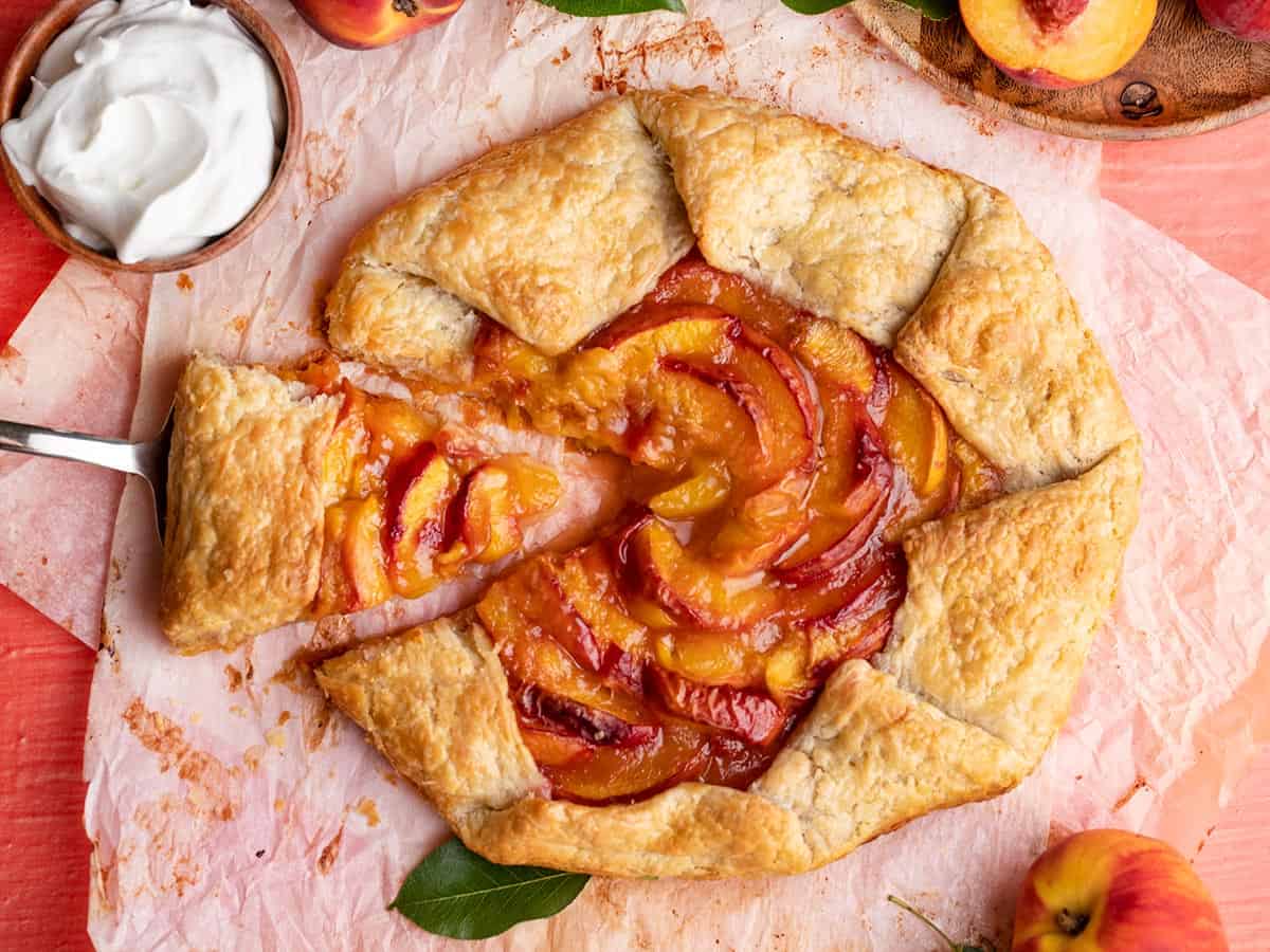 Overhead shot of peach galette with one slice being removed.