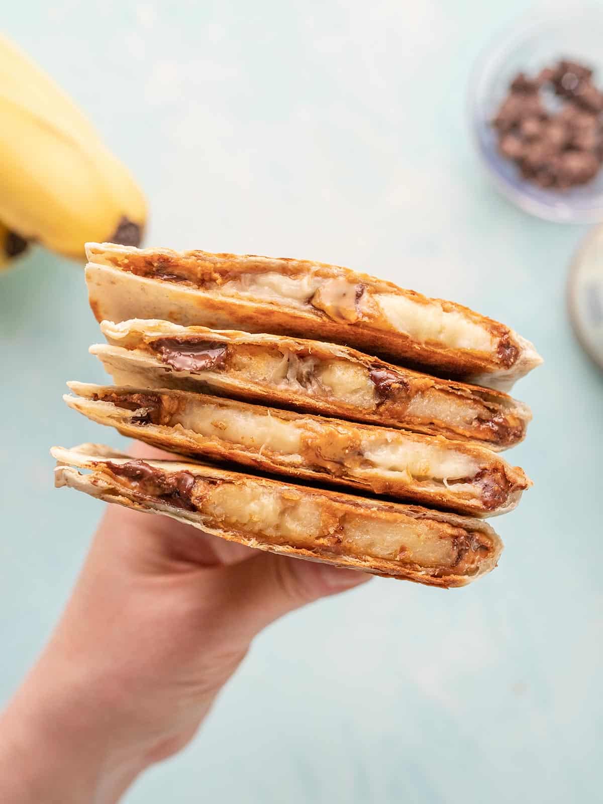 A hand holding a stack of peanut butter banana quesadillas.
