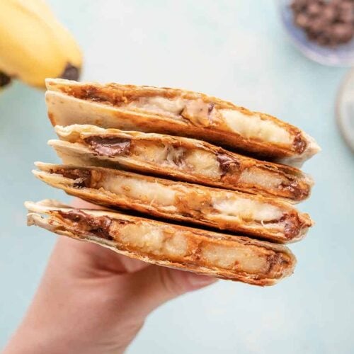 A hand holding a stack of peanut butter banana quesadillas.