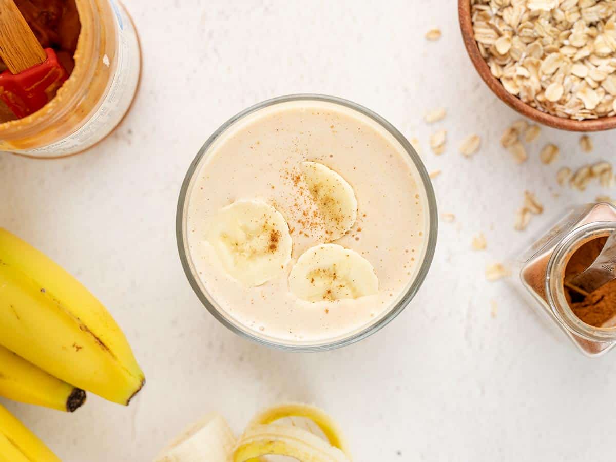 Overhead view of a peanut butter banana smoothie in a glass with cinnamon.