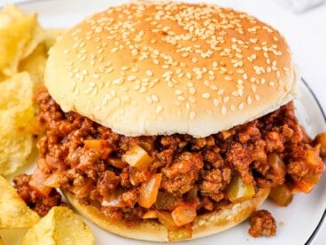 Close up view of a sloppy joe sandwich on a plate with chips
