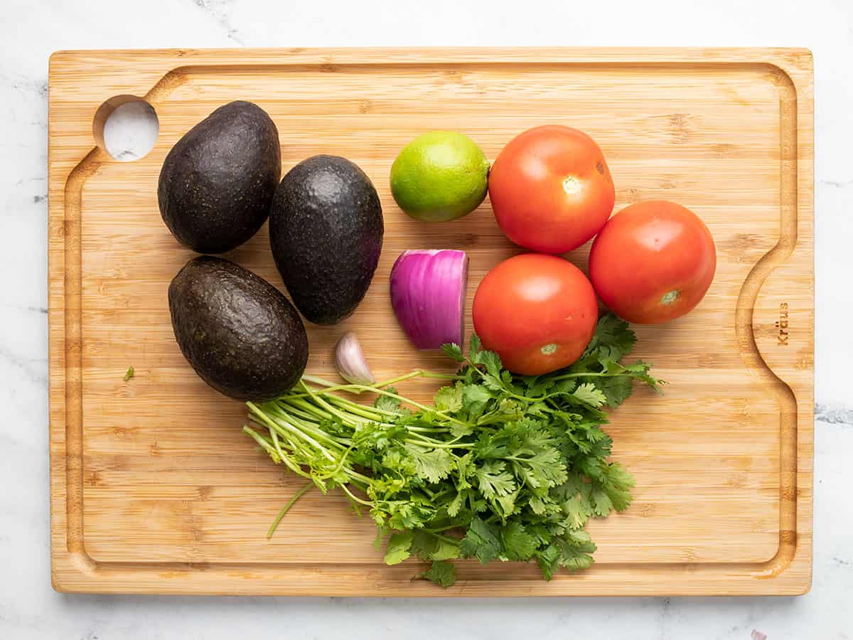 Avocado and tomato salad ingredients on a cutting board.
