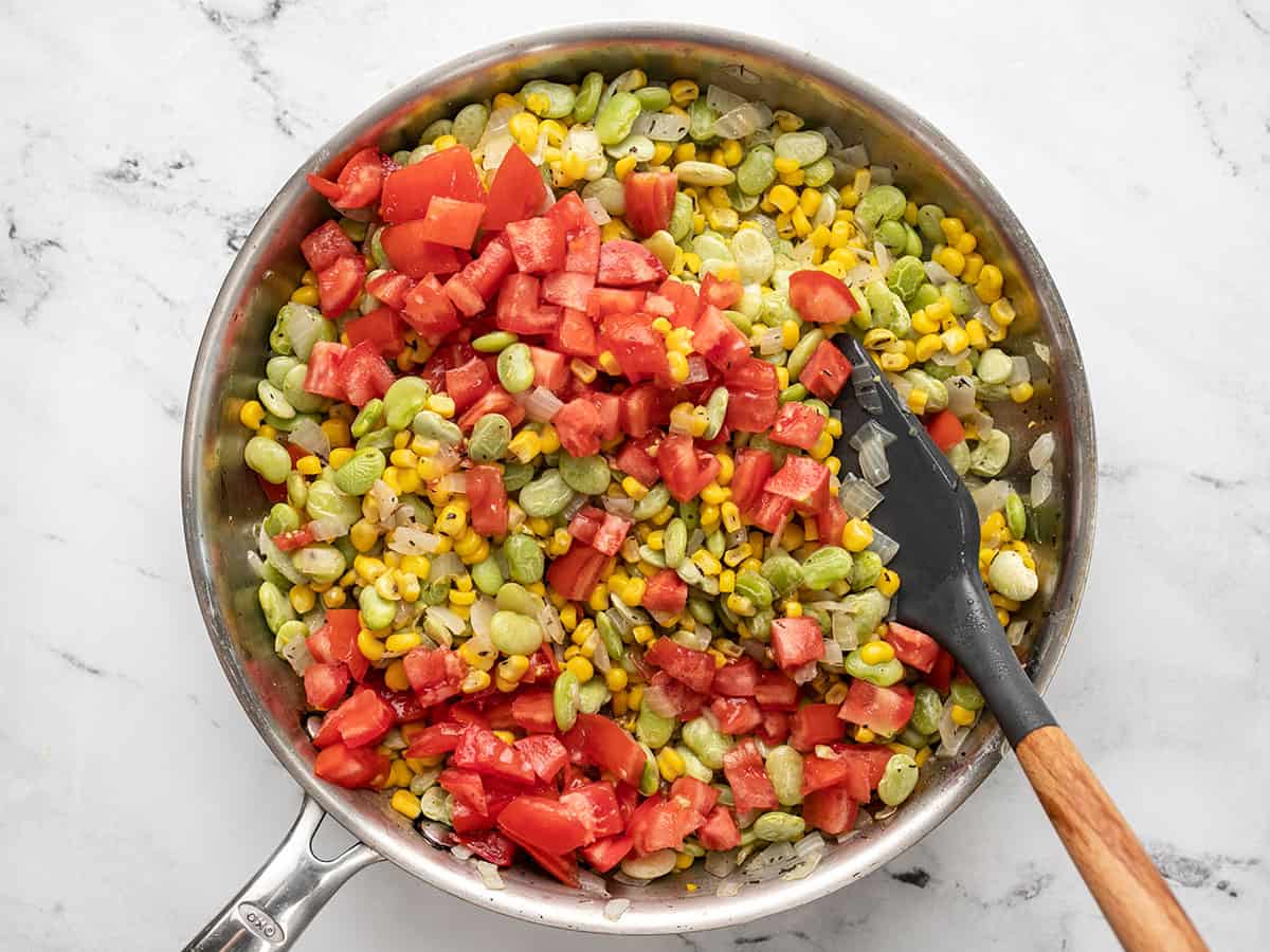 Diced tomatoes being stirred into the skillet.