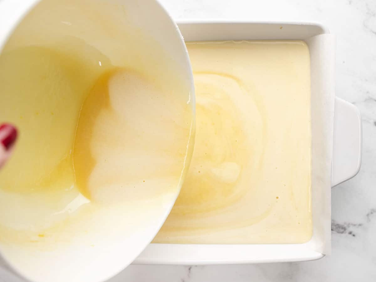 Custard being poured into the baking dish on top of the crust.