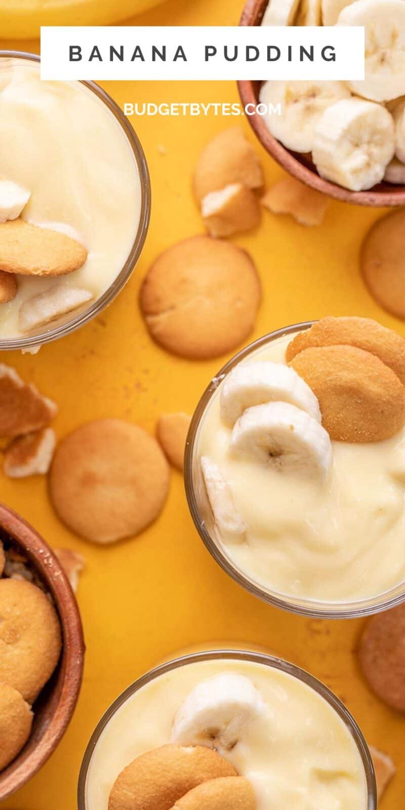 Overhead shot of three glasses of banana pudding with wafers scattered on the counter.