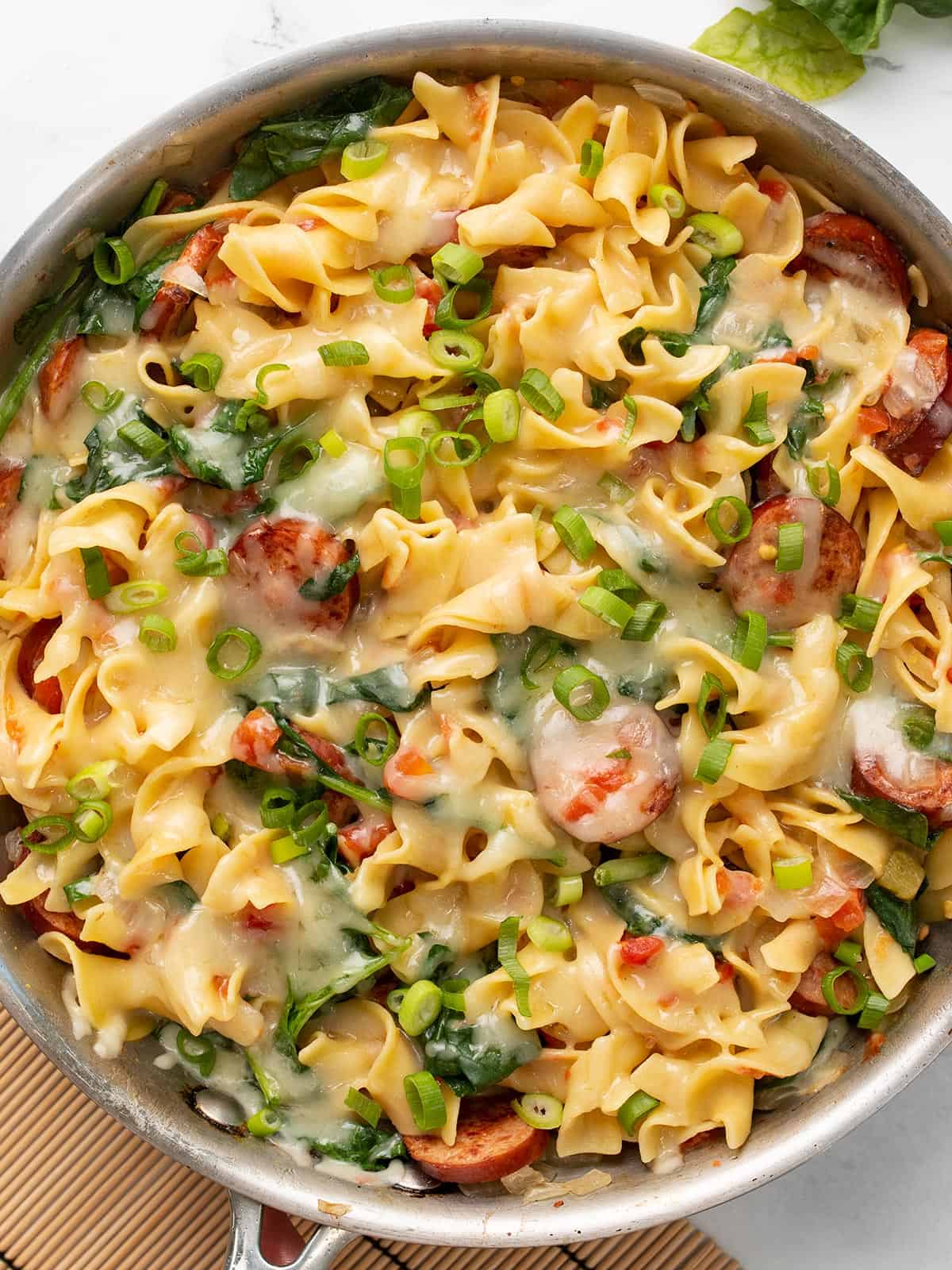 Overhead view of a skillet full of cheesy sausage pasta.