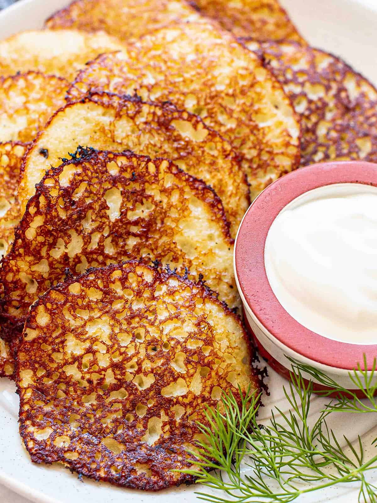 Close up of potato pancakes on a plate with sour cream.