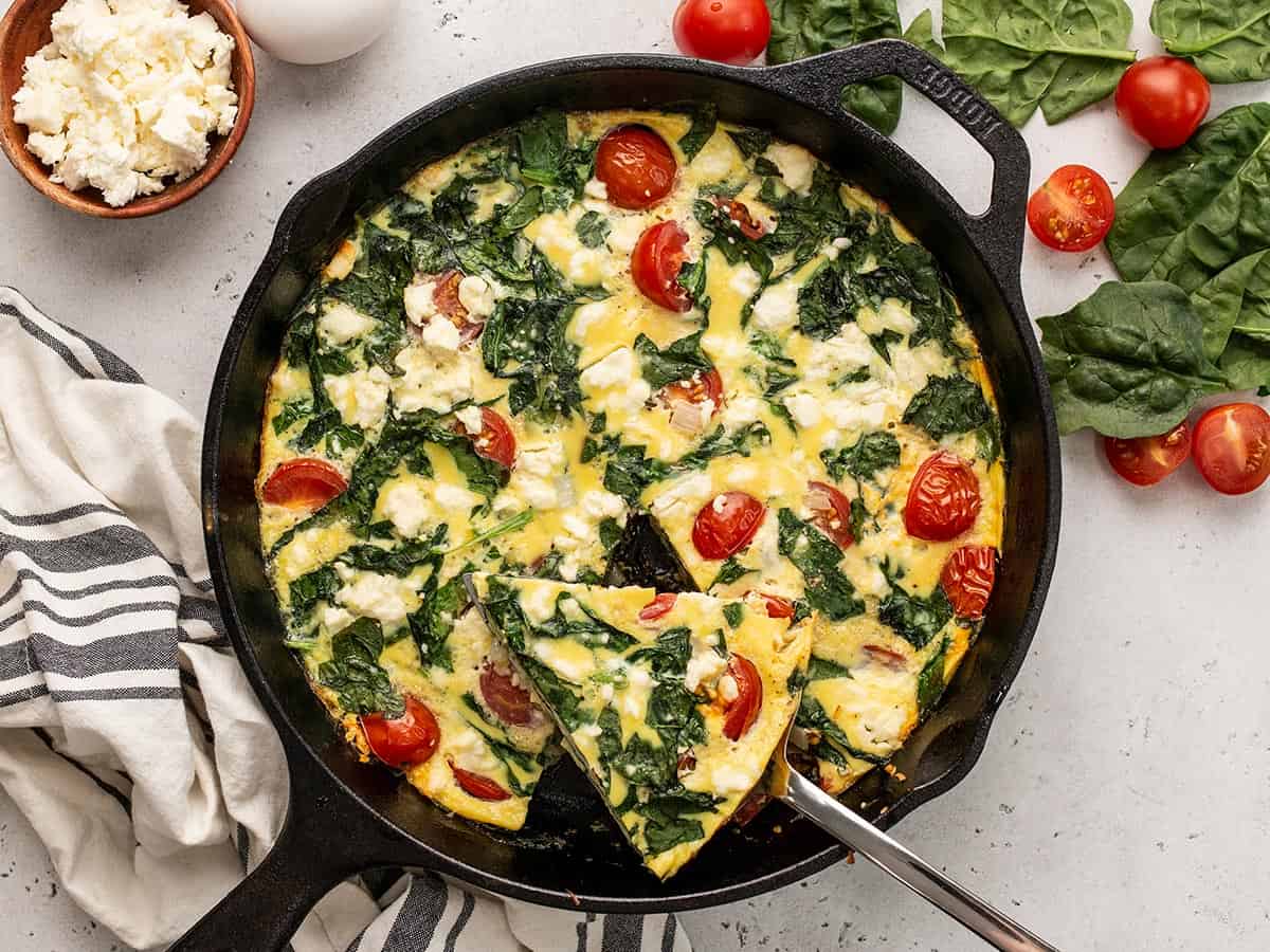 Sliced frittata in the skillet, one slice being lifted.