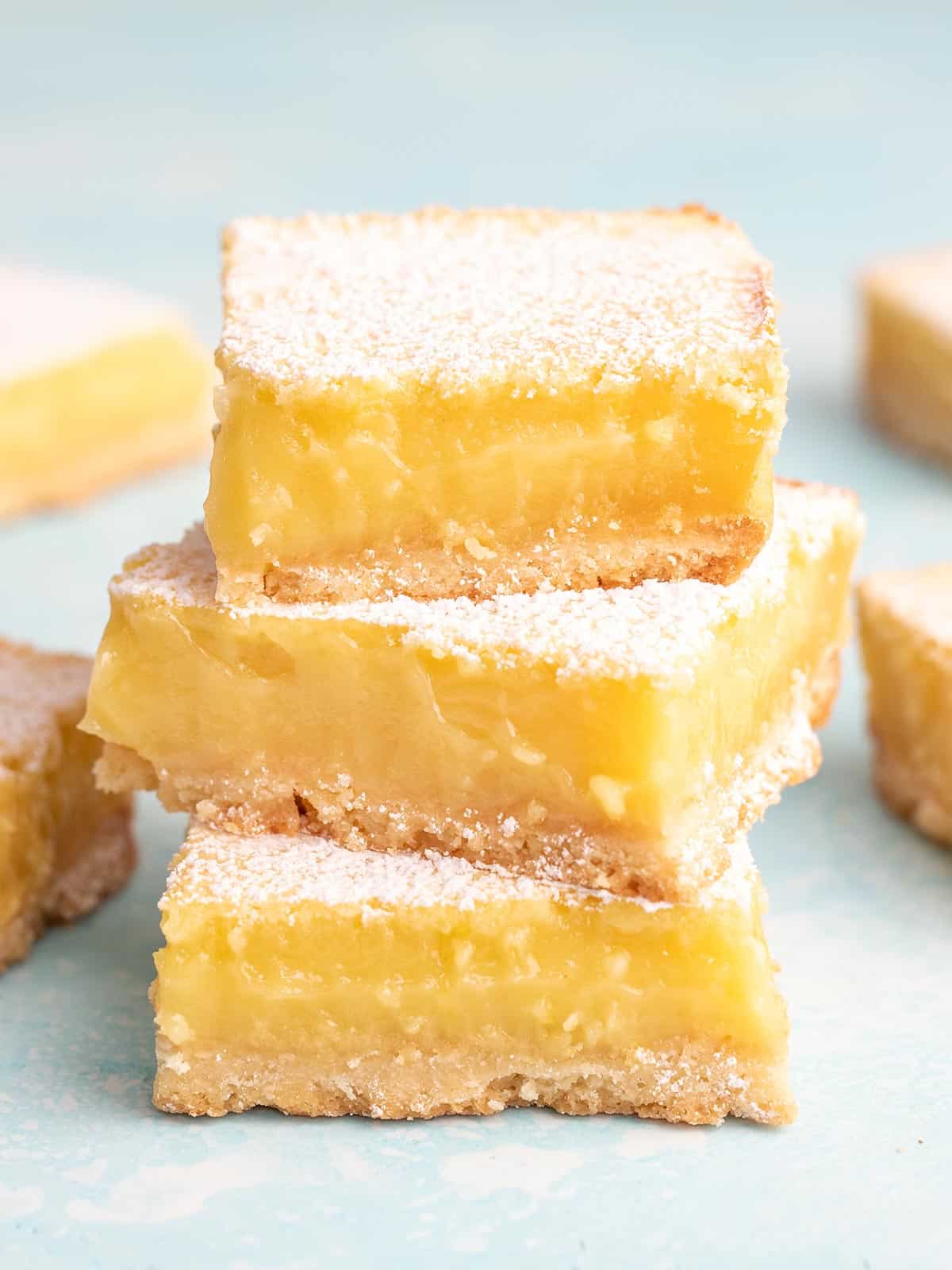 A stack of three lemon bars on a blue background.