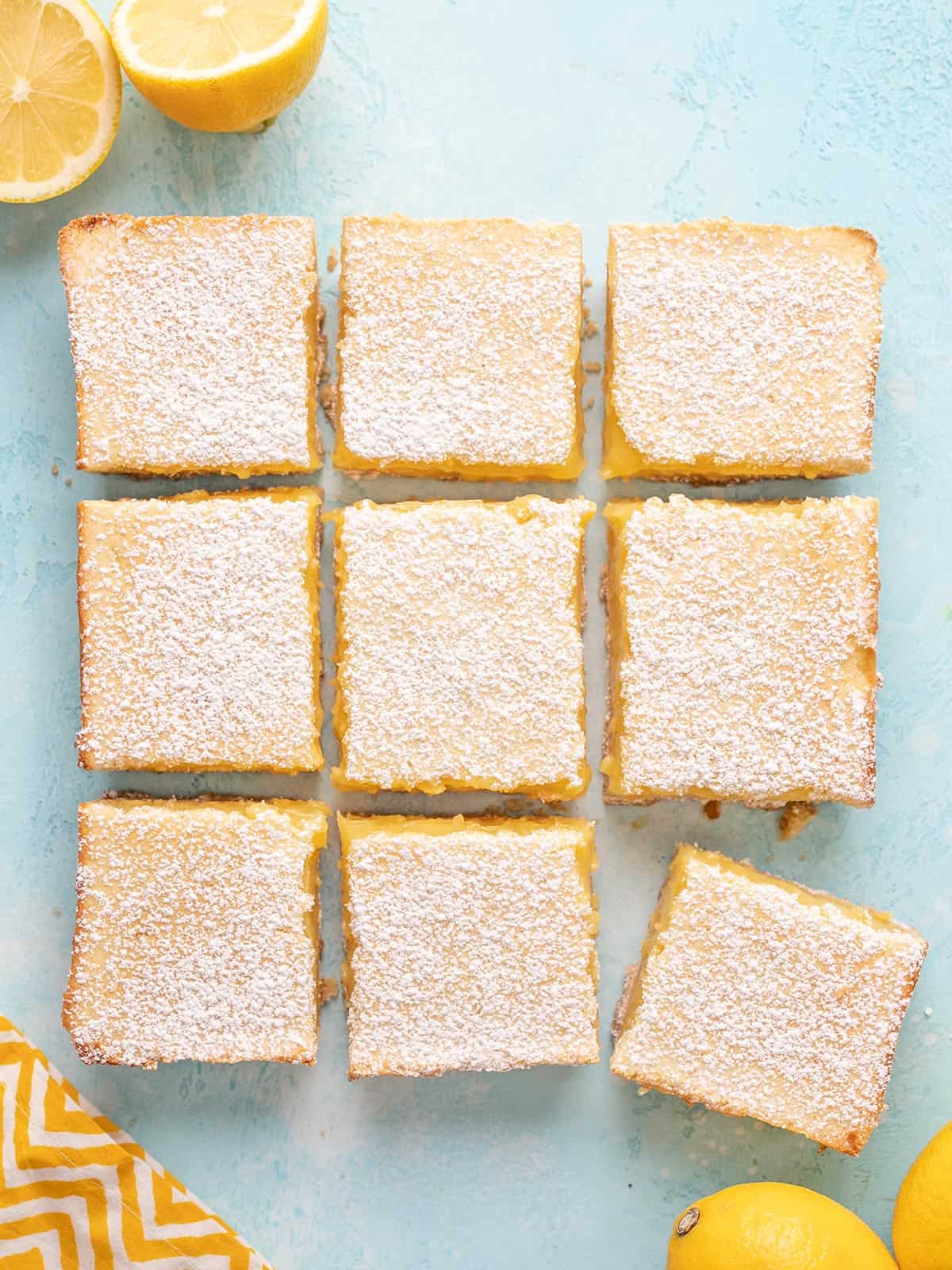 Overhead view of sliced lemon bars on a blue background.