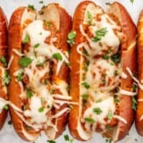 Overhead view of baked meatball subs garnished with parsley.