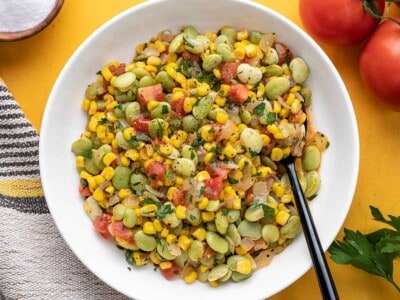 Overhead view of a bowl of succotash with a black spoon.