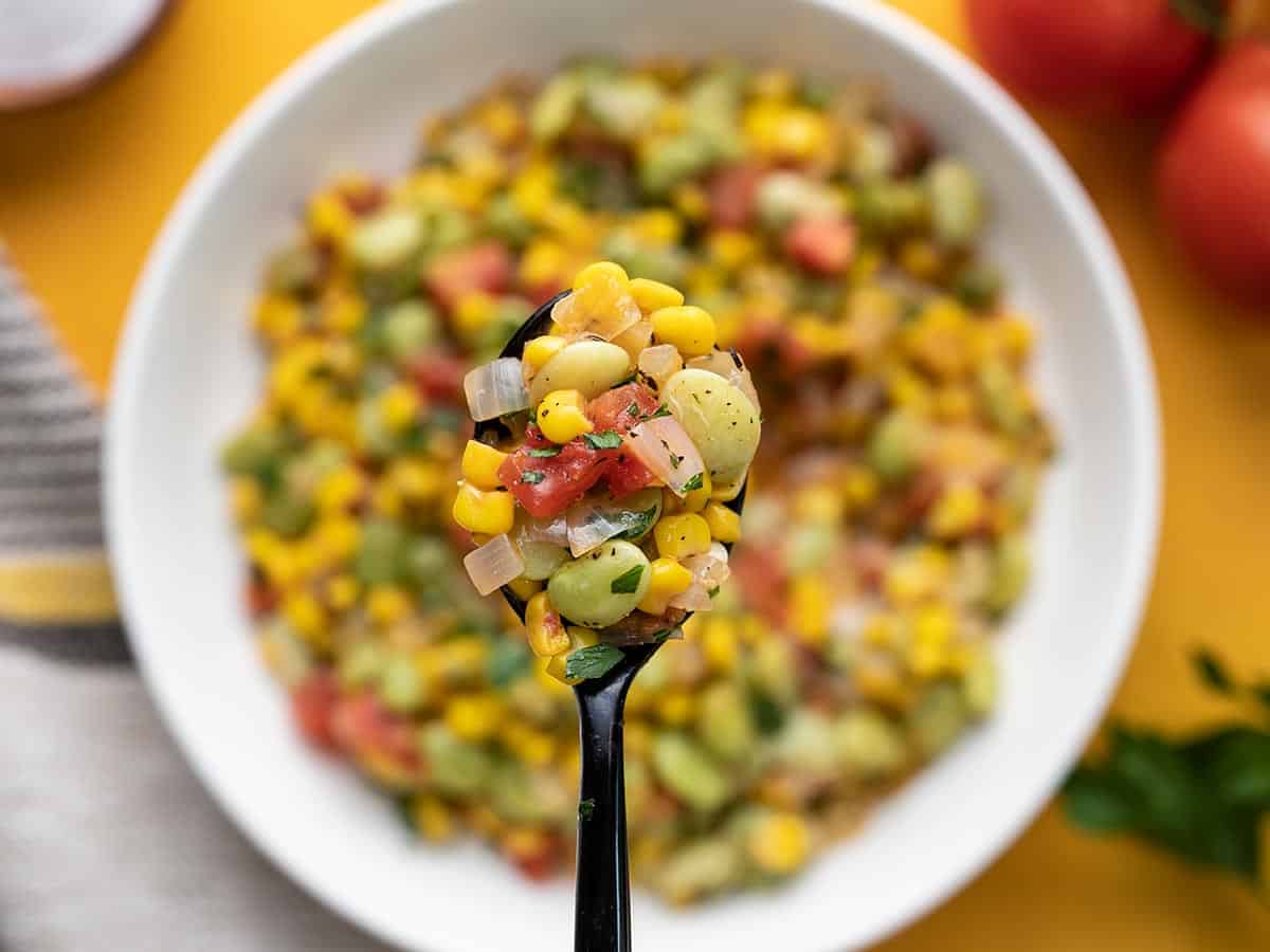 A spoonful of succotash held close to the camera.