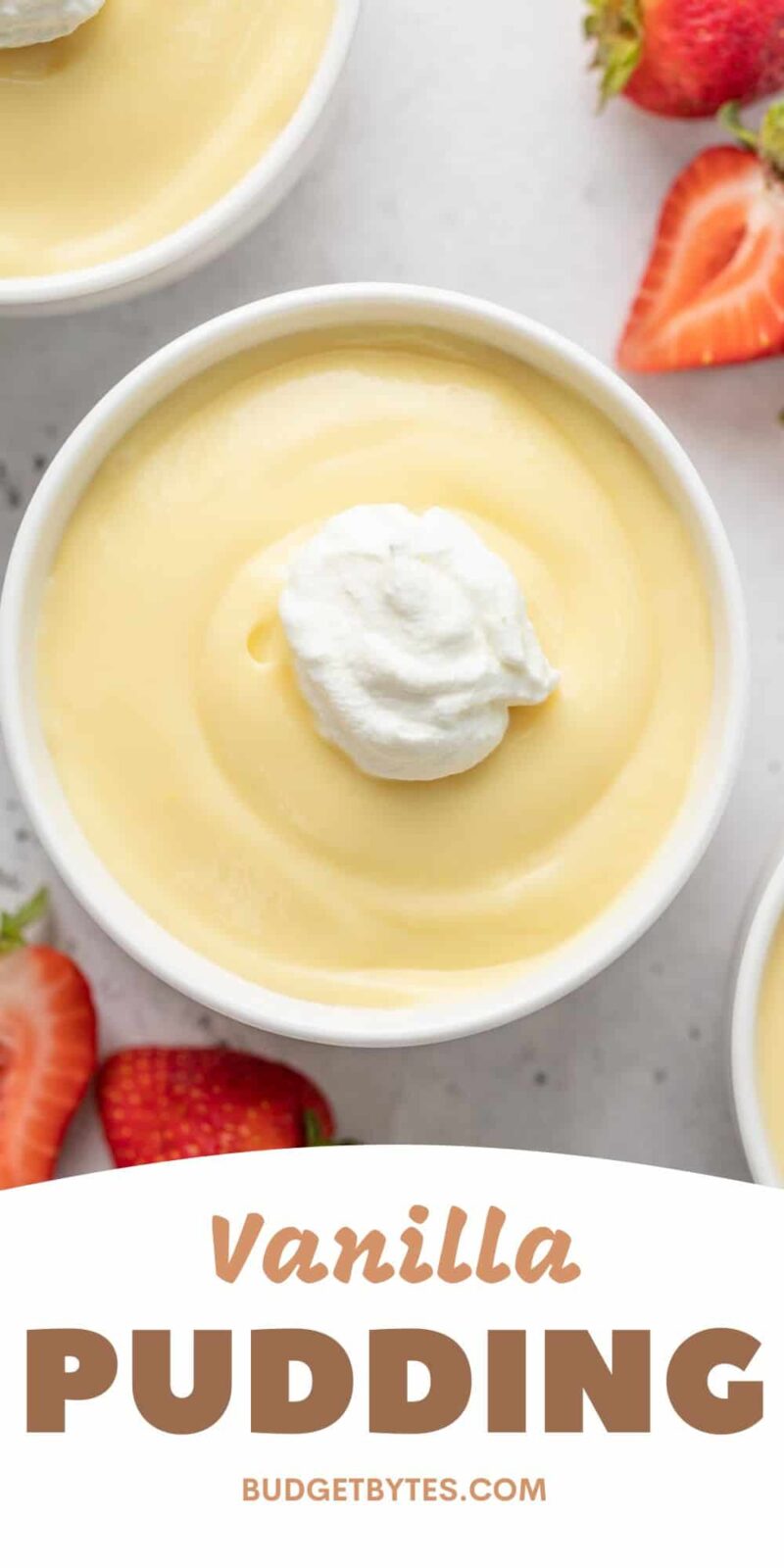 Overhead shot of vanilla pudding in a white bowl with a dollop of whipped cream and sliced strawberries next to it.
