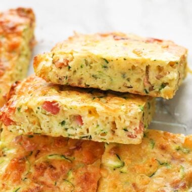 Two slices of zucchini slice laying against the whole casserole.