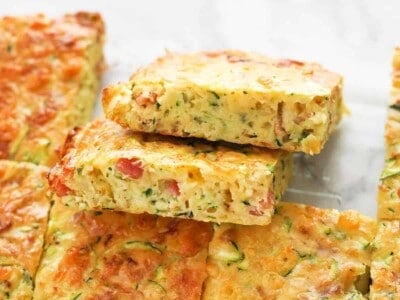 Two slices of zucchini slice laying against the whole casserole.