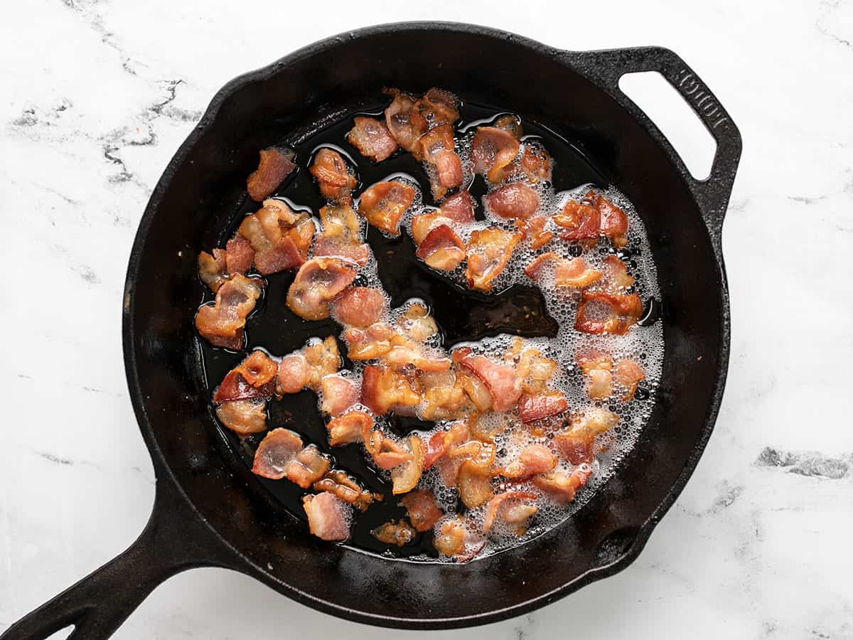 Bacon cooking in a cast iron skillet.