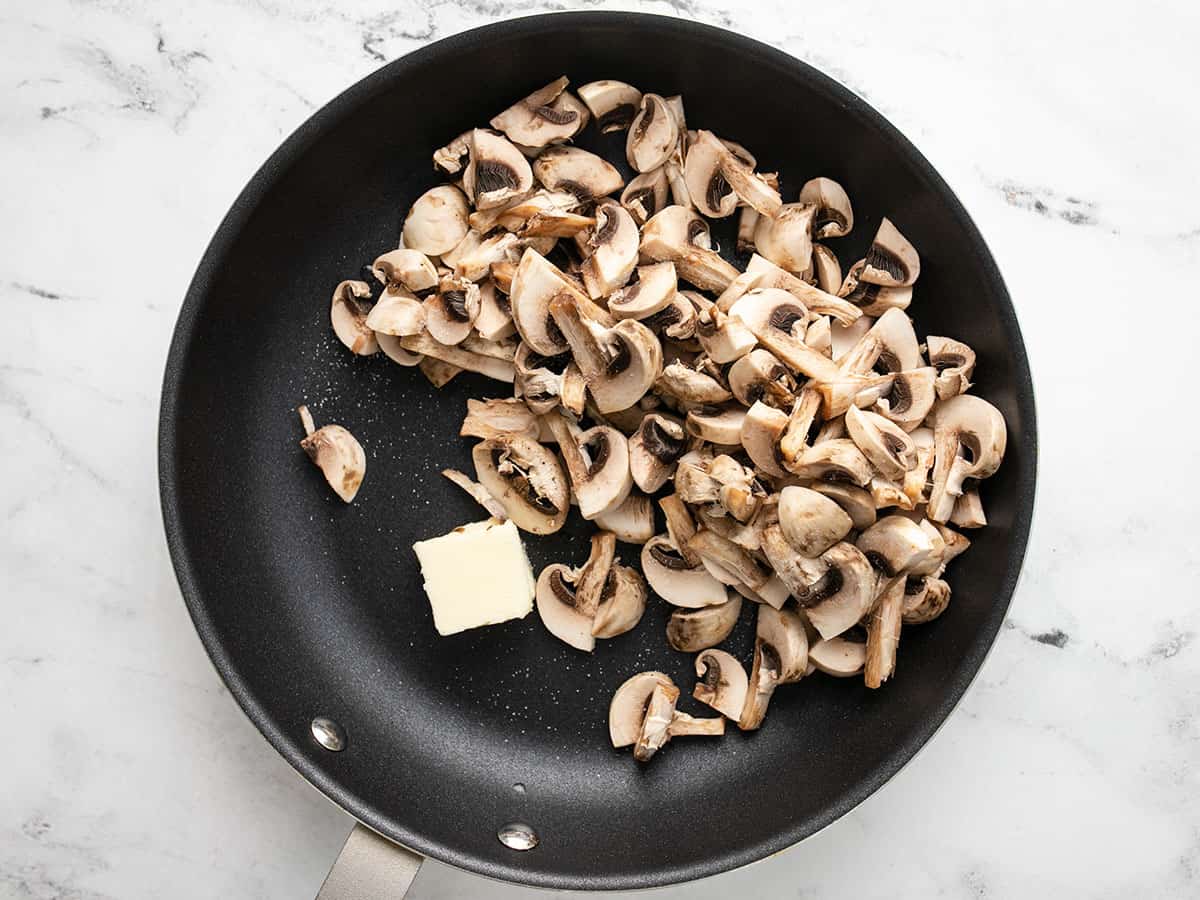 Sliced mushrooms in a skillet with butter.